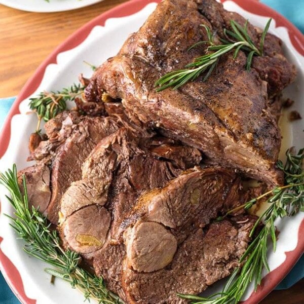 Leg of Lamb on red bordered plate garnished with rosemary