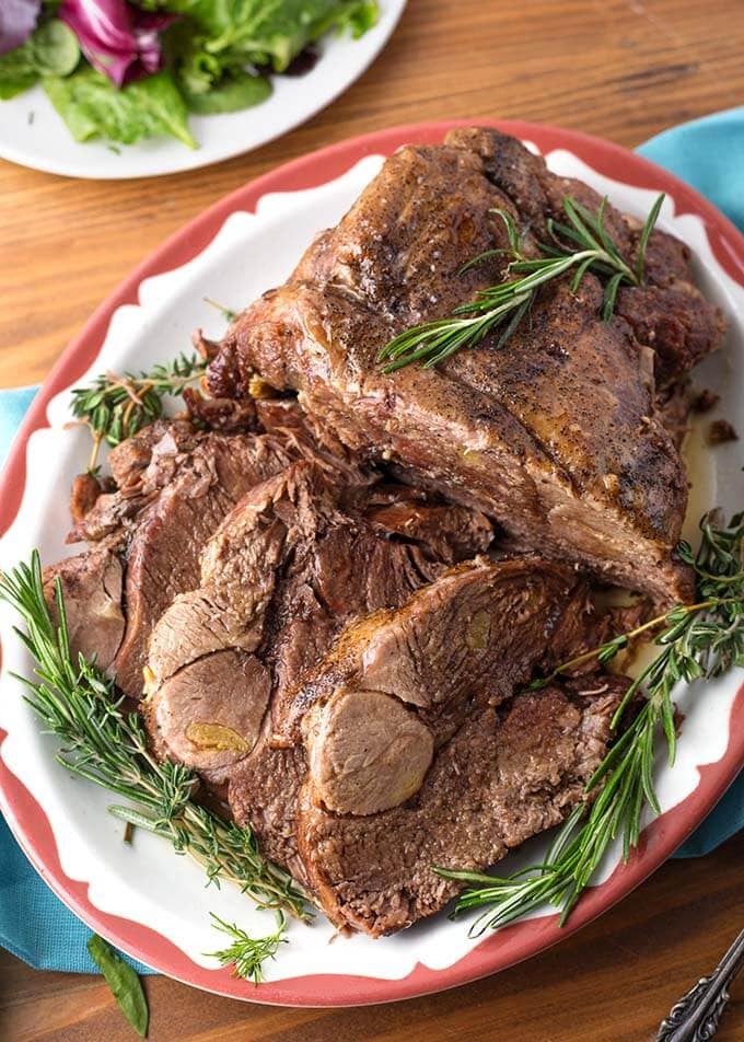 Leg of Lamb on red bordered plate garnished with rosemary