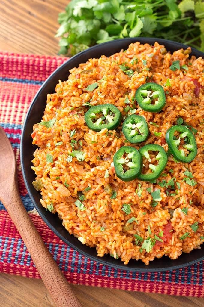 Mexican Rice on a black plate on top of a red and blue stripped mat