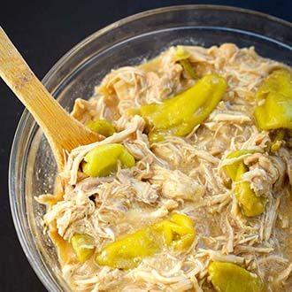 instant pot mississippi chicken in glass bowl with wooden mixing spoon