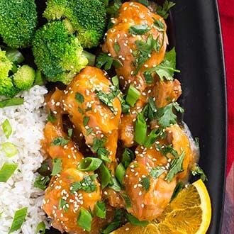 instant pot orange chicken legs with rice and broccoli on black plate