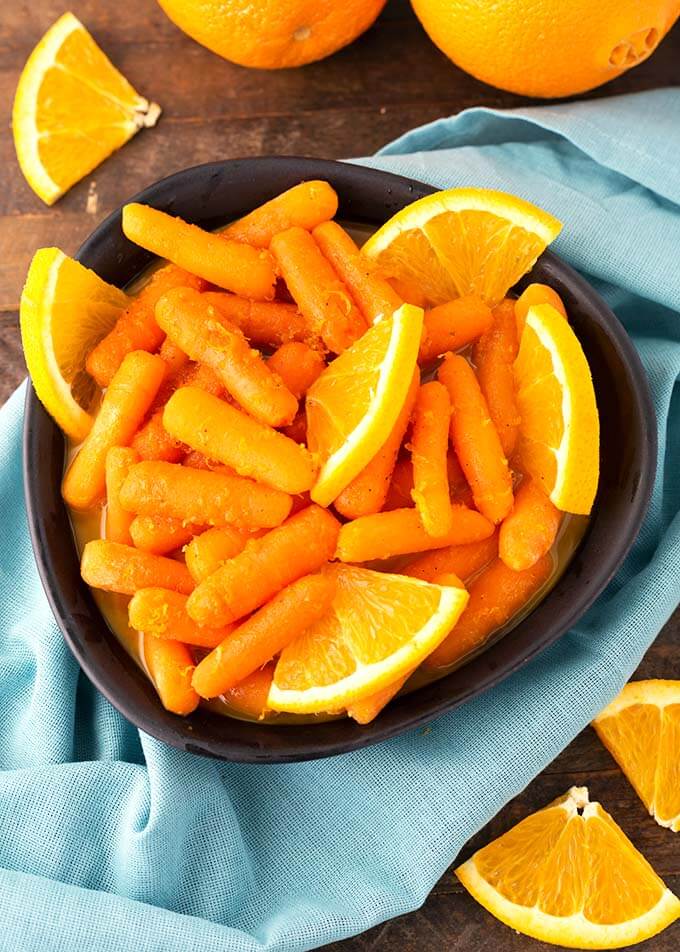 Orange Maple Carrots in a black bowl on top of light blue napkin