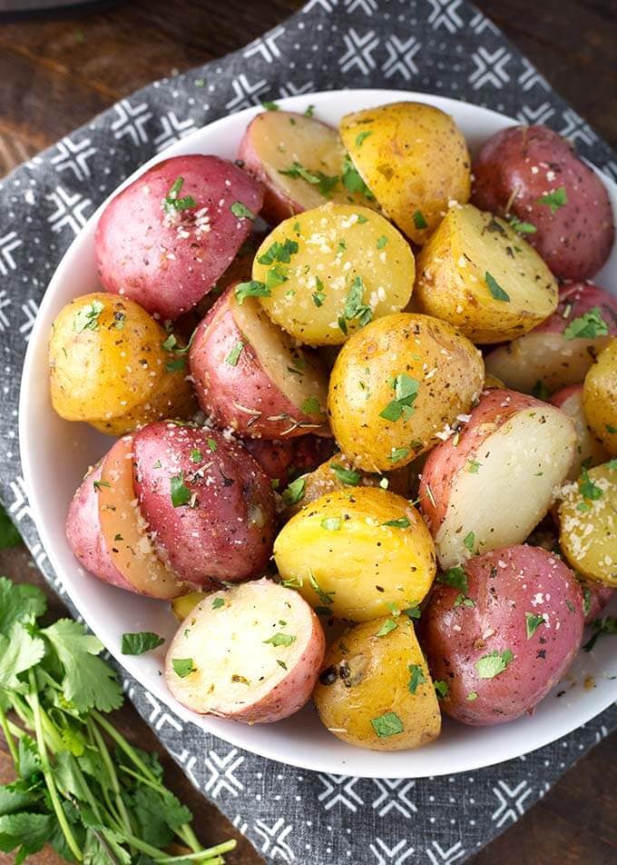 Potatoes with Herb Butter in a white bowl on top of a black and white patterned napkin
