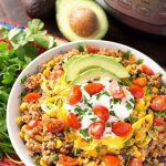 Quinoa Taco Bowl in a white bowl next to a fresh bunch of cilantro all in front of a pressure cooker