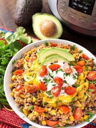 Quinoa Taco Bowl in a white bowl next to a fresh bunch of cilantro all in front of a pressure cooker