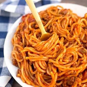 spaghetti on a white plate with gold fork