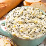 Spinach Artichoke Dip in a turquoise bowl next to slices of bread