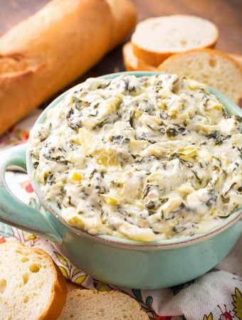 Spinach Artichoke Dip in a turquoise bowl next to slices of bread