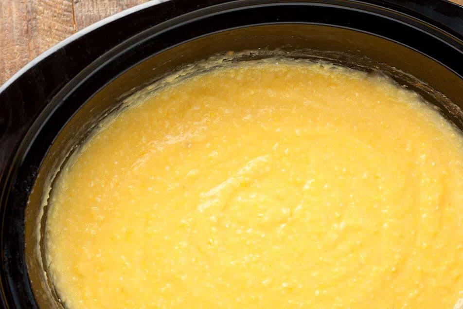 Slow Cooker Cheesy Grits in a black crock