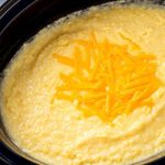 Cheesy Grits in a slow cooker topped with shredded cheese