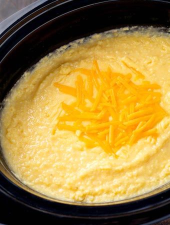 Cheesy Grits in a slow cooker topped with shredded cheese