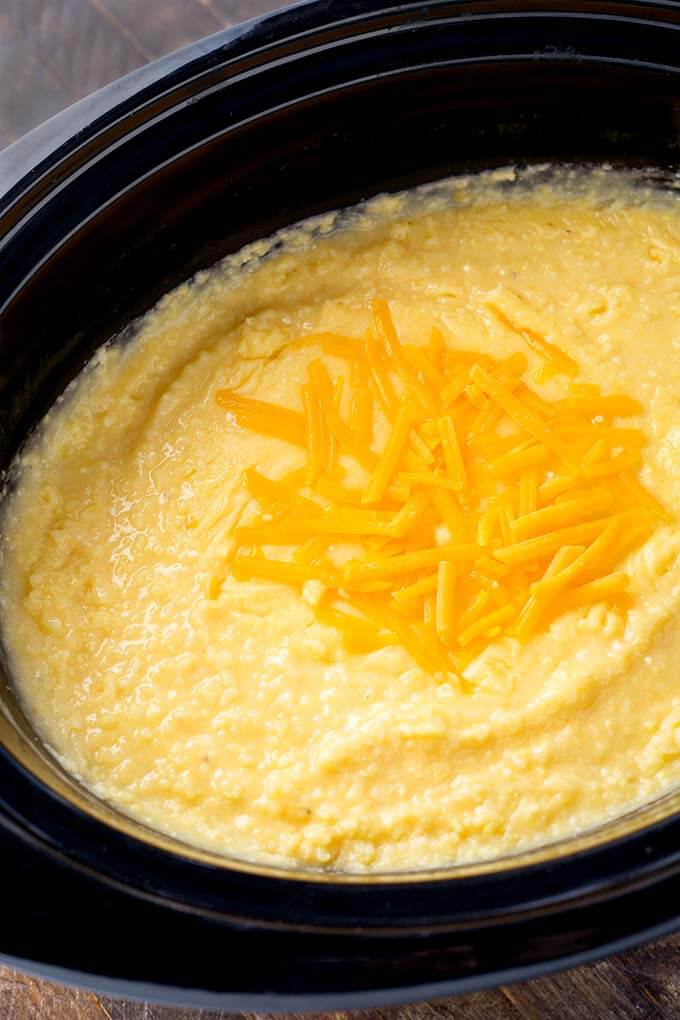 Cheesy Grits in a slow cooker topped with shredded cheese