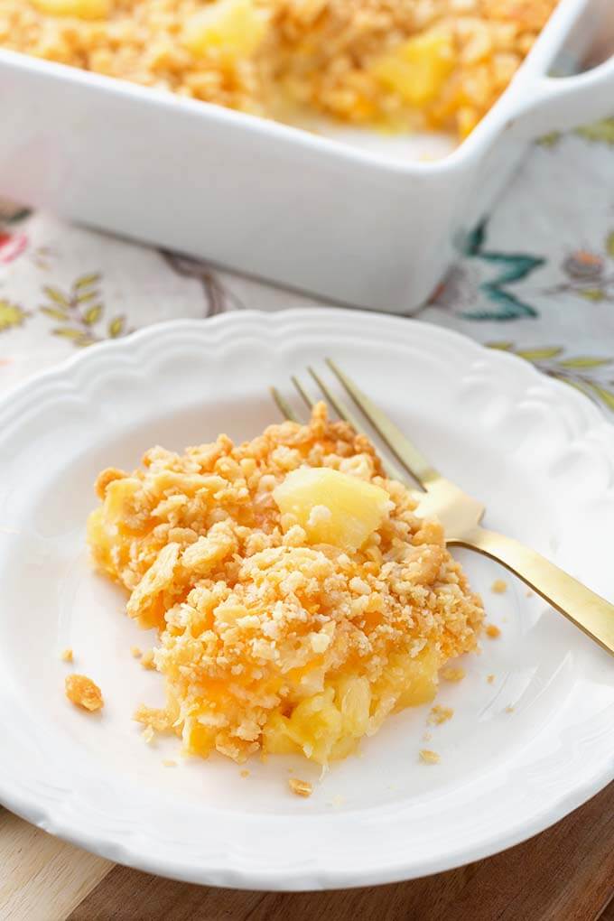 Slice of Southern Pineapple Casserole on white plate with golden fork