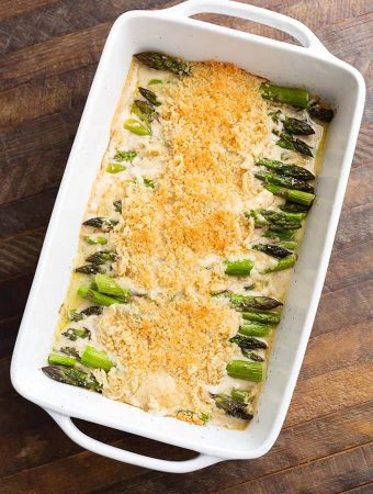 Creamy Baked Asparagus Alfredo in white baking dish on wooden surface