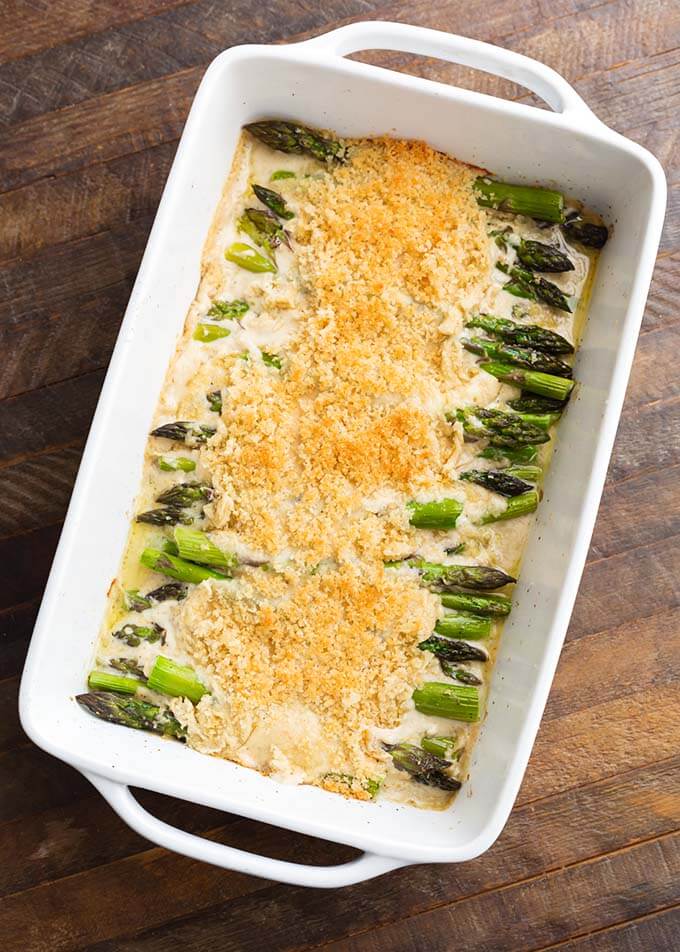 Creamy Baked Asparagus Alfredo in white baking dish on wooden surface