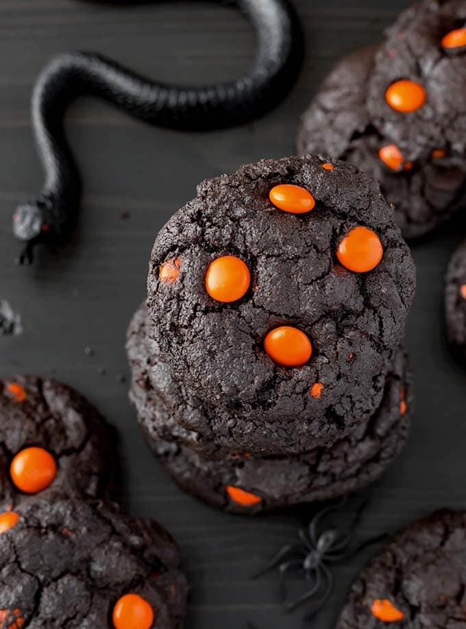 Stacked Dark Chocolate Halloween Cookies next to black plastic spider and snake