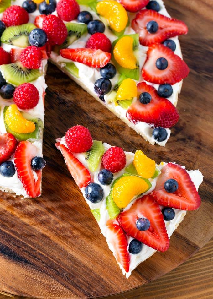 Slice of Fresh Fruit Pizza being removed from the whole