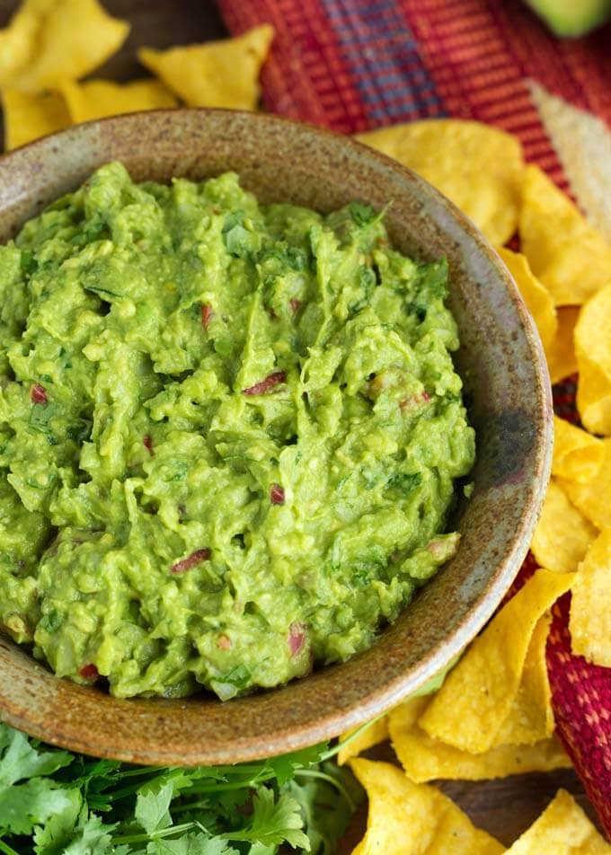 Fresh Homemade Guacamole in a brown bowl next to corn tortilla chips