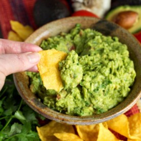 Fresh Homemade Guacamole on a chip in hand