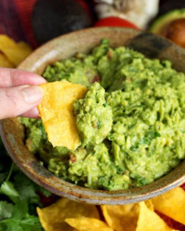 Fresh Homemade Guacamole on a chip in hand