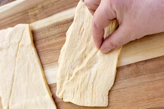 hand pinching the seam of croissant dough together