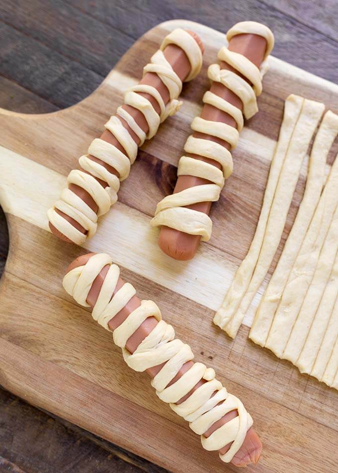 Hot dogs wrapped with dough on wooden board