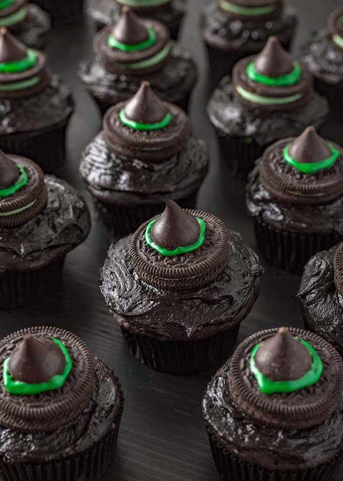 Several Halloween Witch Hat Cupcakes on dark wood board