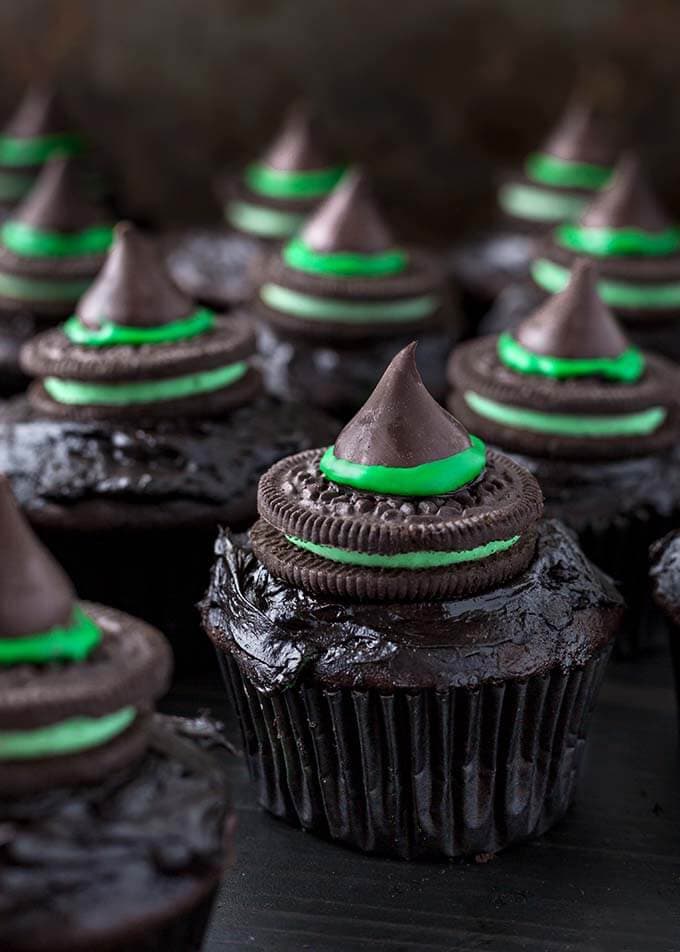 Several Halloween Witch Hat Cupcakes on dark wood board
