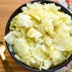 Buttered Cabbage in a black bowl on wooden surface