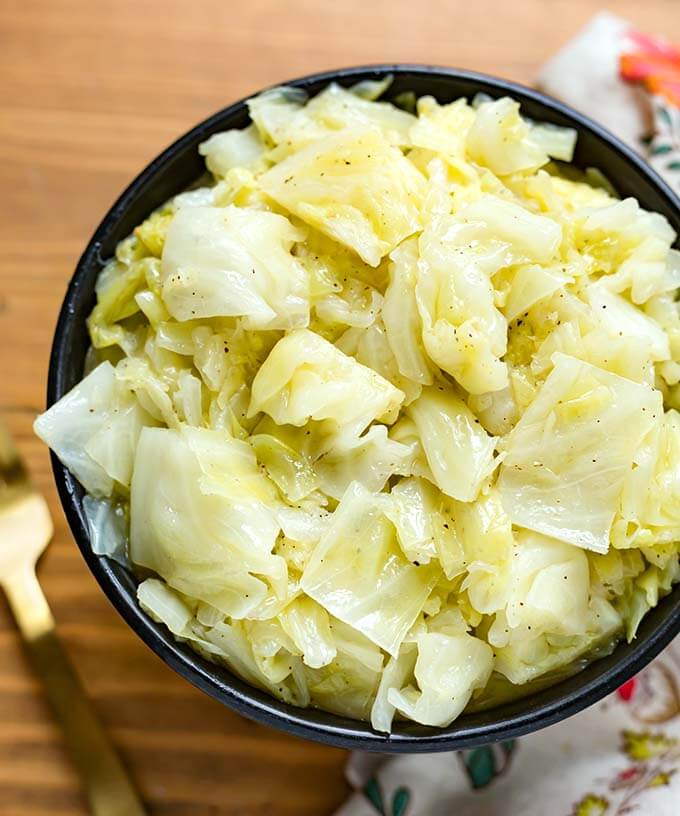 Buttered Cabbage in a black bowl on wooden surface