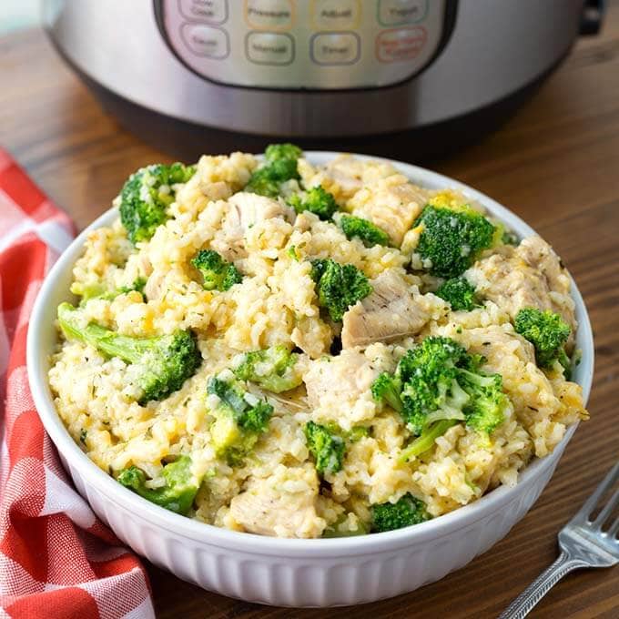 Chicken Broccoli Rice Casserole in a white bowl in front of a pressure cooker