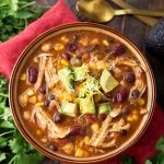 Chicken Taco Soup in a brown bowl on a red napkin next to fresh cilantro