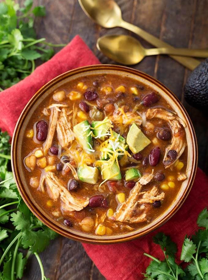 Chicken Taco Soup in a brown bowl surrounded by bunches of fresh cilantro