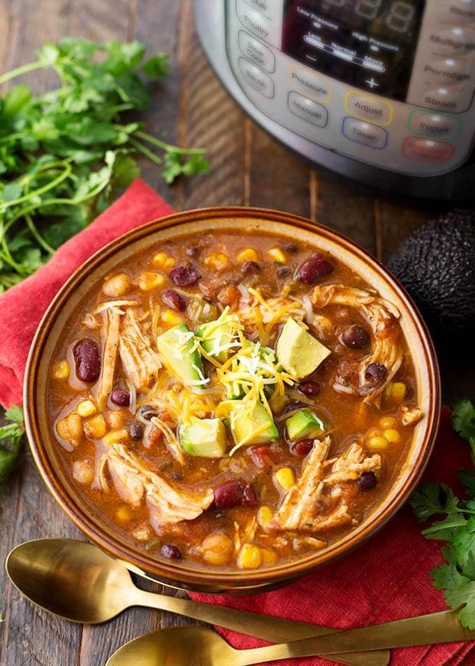 Chicken Taco Soup in a brown bowl on a red napkin next to fresh cilantro