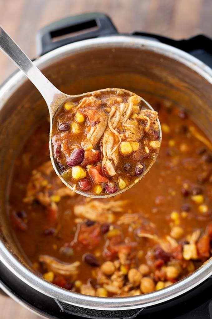 Closeup of ladle full of Chicken Taco Soup over pressure cooker