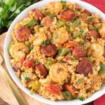 Jambalaya in a white bowl on a wooden board