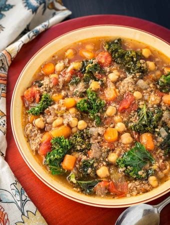 Tuscan Sausage Kale Soup in brown bowl on wooden board