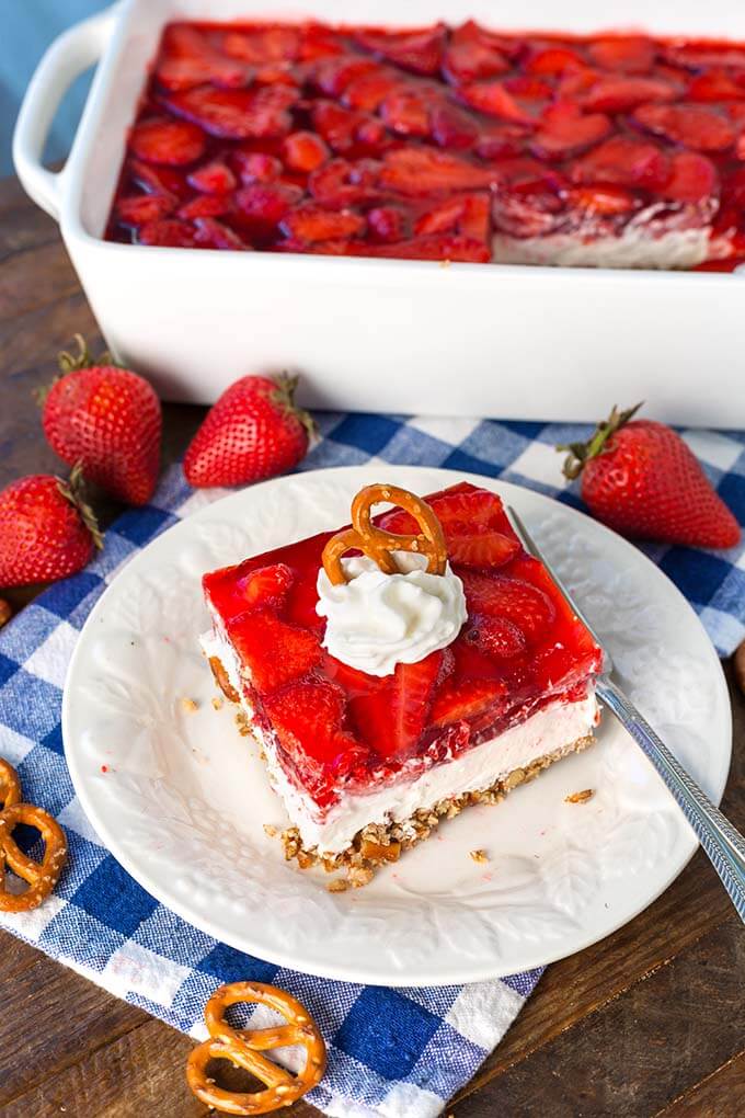 Slice of Strawberry Pretzel Jello Salad on white plate in front of white baking dish