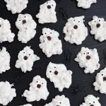 White Chocolate Halloween Ghosts and black plastic spiders on dark wood background