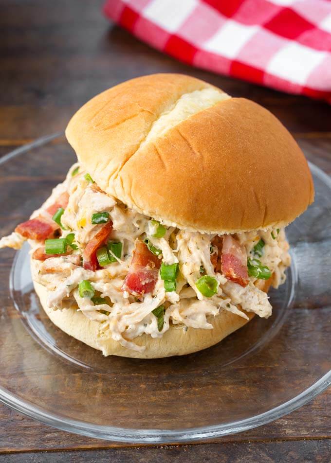 Slow Cooker Crack Chicken on a hamburger bun on a glass plate