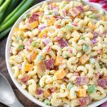 Classic Macaroni Salad in white bowl next to red gingham napkin and silver spoon