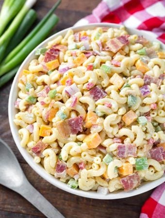 Classic Macaroni Salad in white bowl next to red gingham napkin and silver spoon