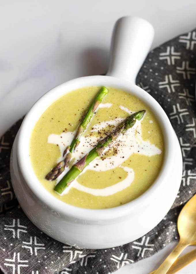 Close up of Asparagus Soup in a white bowl on a black patterned napkin