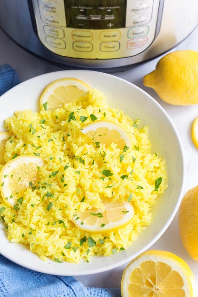 Lemon Rice in white bowl with sliced lemons in front of pressure cooker