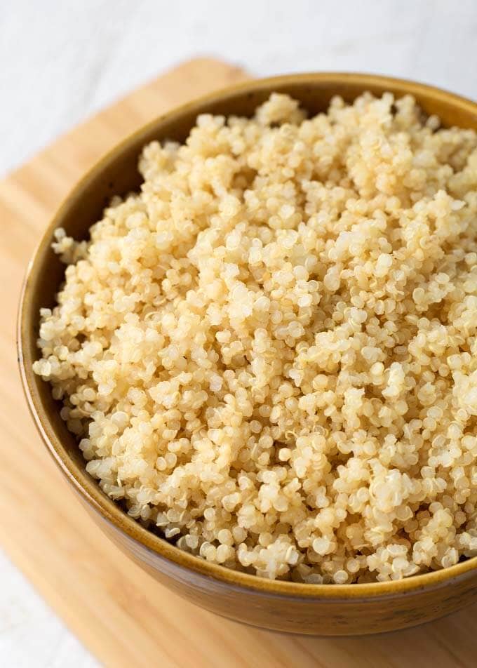 Quinoa in a brown bowl on wooden board