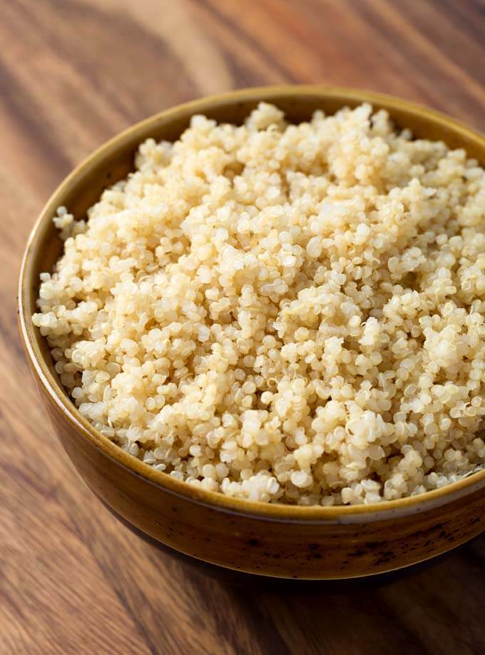 Quinoa in a brown bowl on wooden surface