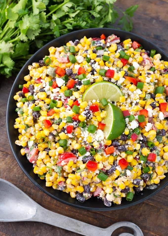 Mexican Street Corn Salad on a black plate on a wooden surface