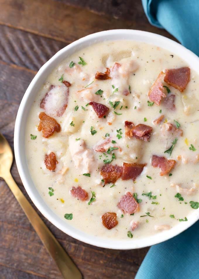 Slow Cooker Clam Chowder in a white bowl on a wooden surface