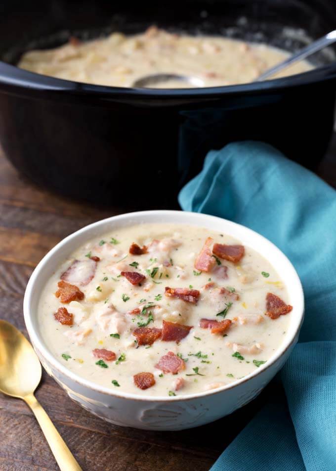 Clam Chowder in a white bowl in front of a slow cooker