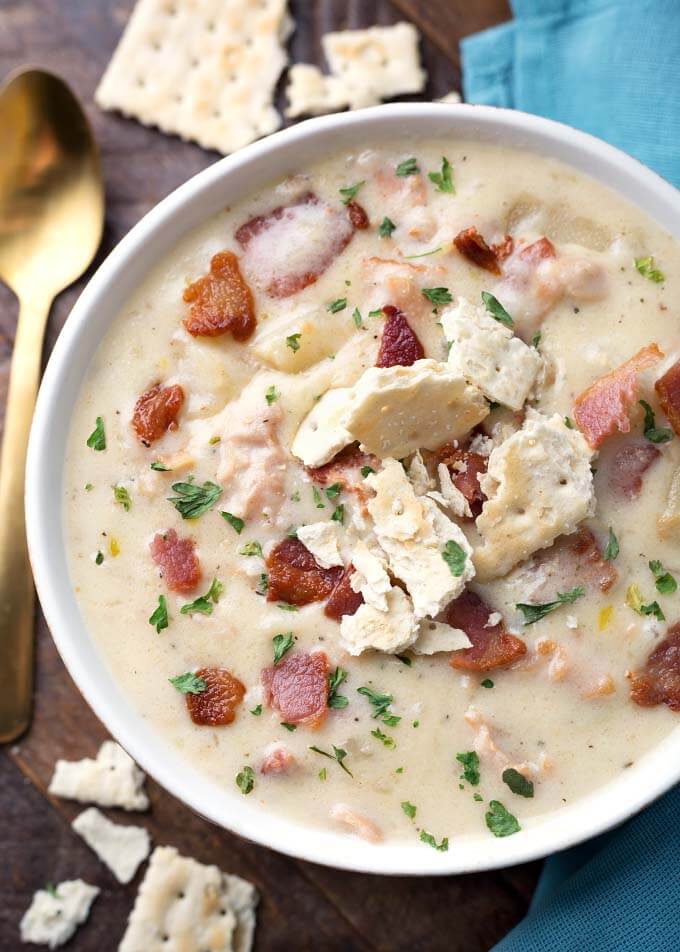Close up of Clam Chowder in a white bowl garnished with broken crackers